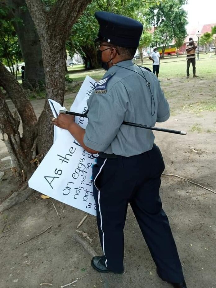 Photo: A police officer seen while going about taking away placards from individuals at Independence Square on Monday 2nd August 2021 (social media image)